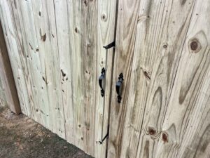 A close-up view of a wooden fence gate with black decorative handles and latch by Fencingphd.nc in Fayetteville, NC.