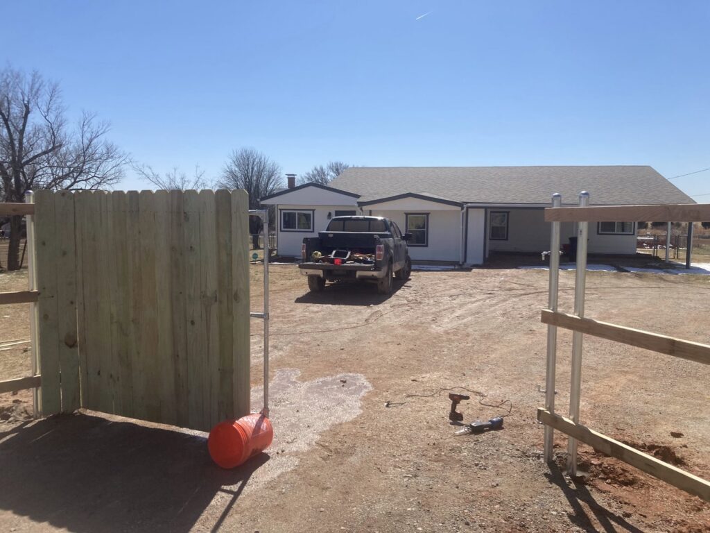 A wooden fence gate being installed at a property entrance by 12 Corners Fence Company in Tecumseh, OK