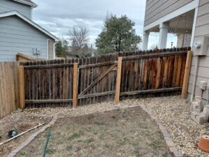 An old wood fence with a gate that has been repaired and reinforced with new posts by Done Wright Fencing and Welding in Denver, CO.