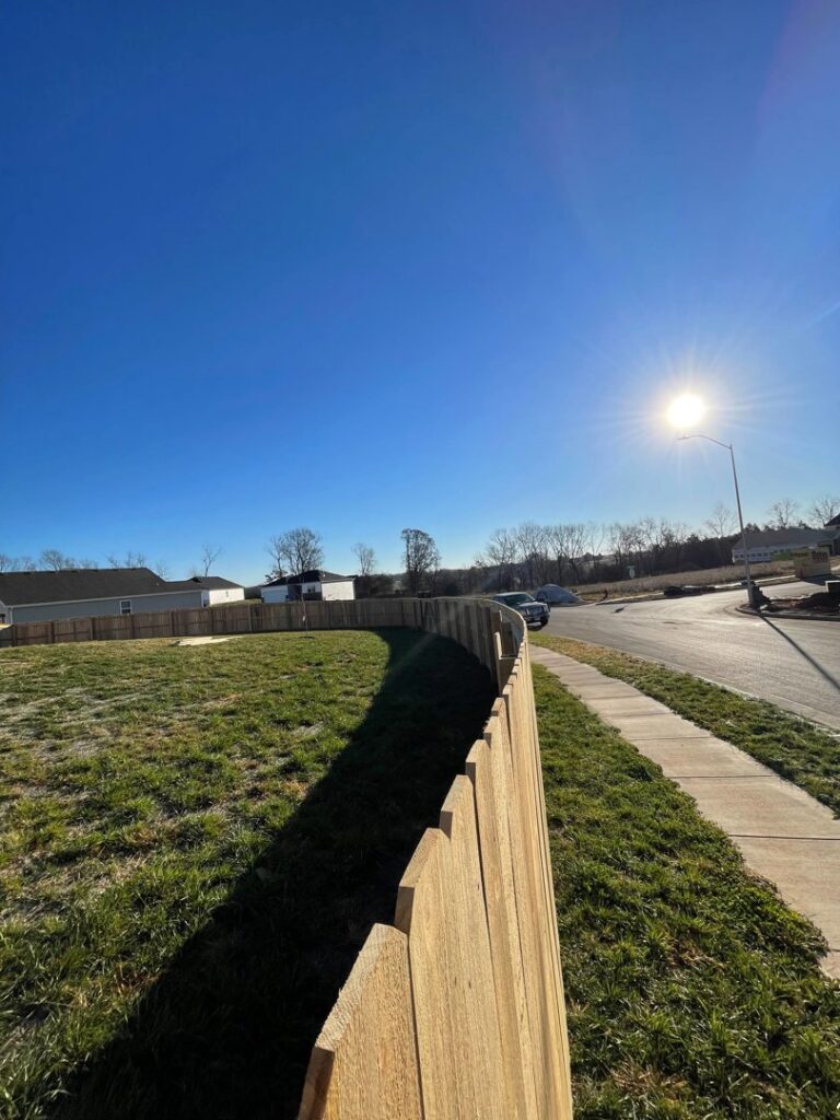 A newly installed light wood fence running along a sidewalk by Axiom Fence LLC in Springfield, MO.