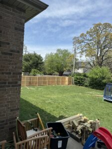 A wood fence installation in progress in a backyard, with materials visible, by Axiom Fence LLC in Springfield, MO.