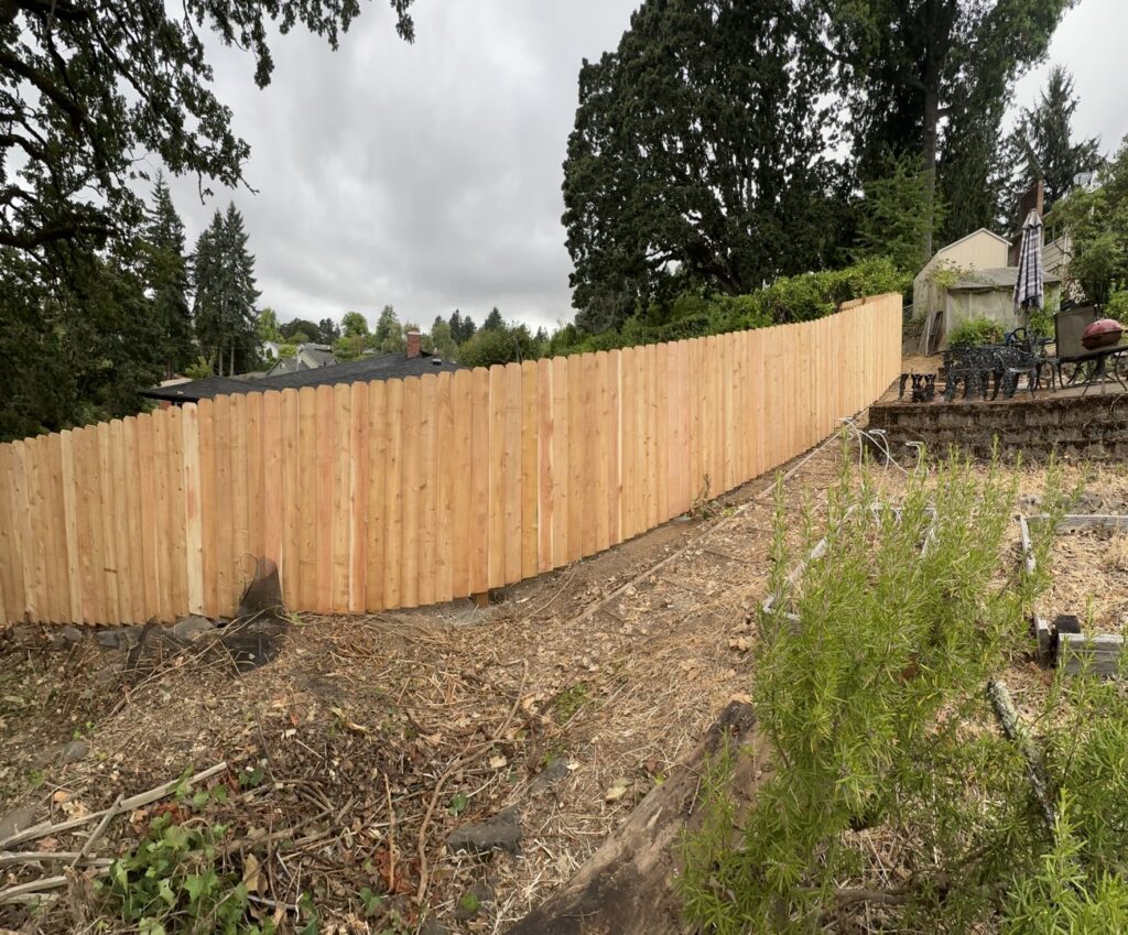A new wood fence installation expertly following the contours of a sloped backyard by RPB Fence in Salem, OR