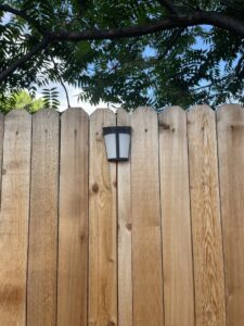 A close-up of a wood fence panel featuring a decorative solar light, installed by Fence Guru LLC in Denver, CO.
