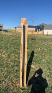 A newly installed wood fence post featuring a black metal insert by Axiom Fence LLC in Springfield, MO.