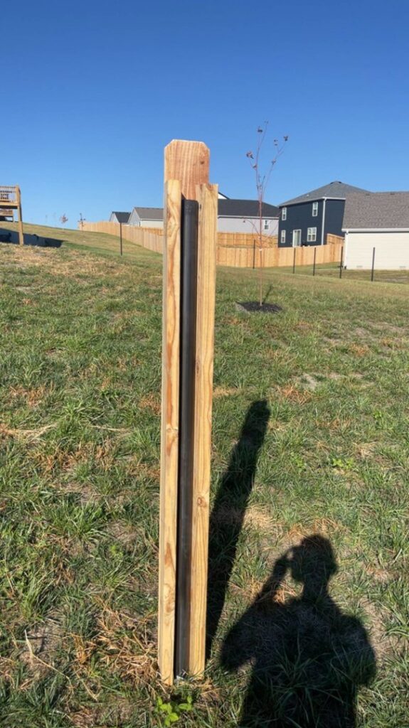 A newly installed wood fence post featuring a black metal insert by Axiom Fence LLC in Springfield, MO.