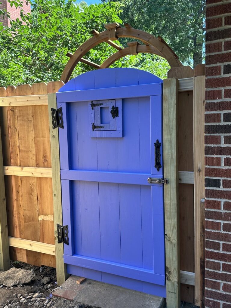 A custom wood fence with a vibrant purple gate and an arched arbor installed by Sergio's Fence in Kansas City, KS.