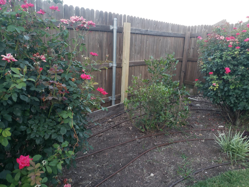 A wooden fence undergoing repair with a new post and metal support by T&G Outdoor Services in Austin, TX.