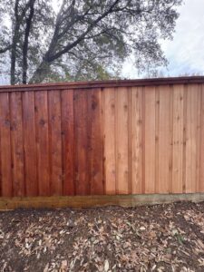 A wooden fence showing a clear before and after comparison of professional staining by True Ways Services LLC in Mesquite, TX.