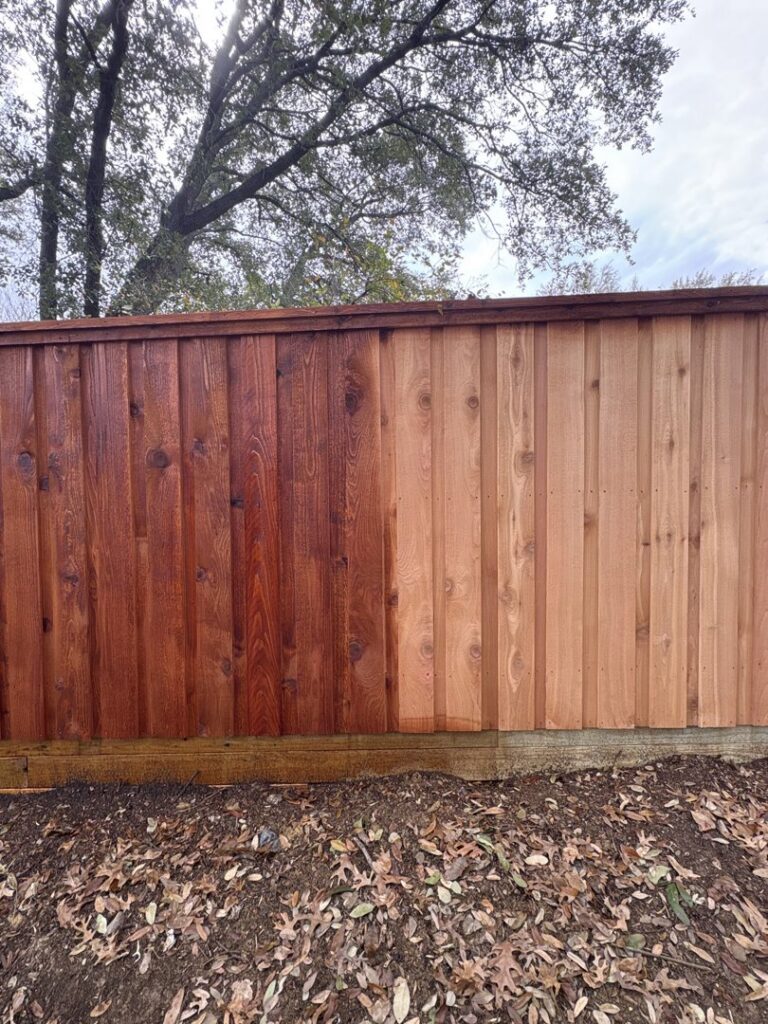 A wooden fence showing a clear before and after comparison of professional staining by True Ways Services LLC in Mesquite, TX.