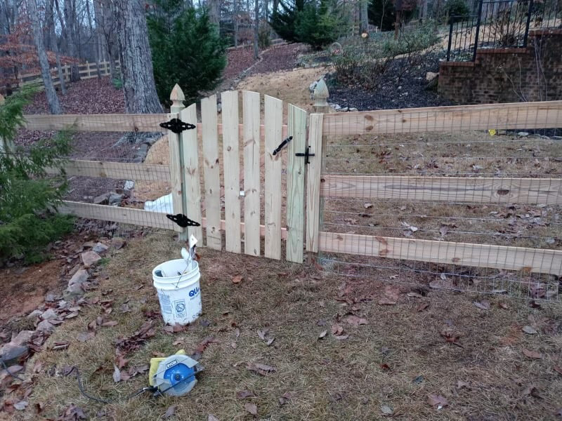 A wooden fence with wire mesh and a newly installed gate by Castillo Fences in Sacramento, CA.