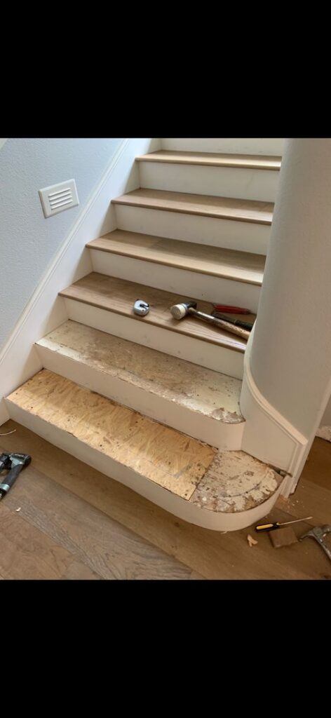 Wood flooring installation in progress on a staircase, showing tools and unfinished steps by Anaheim Carpet and Flooring in Anaheim, CA.