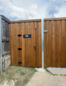 A custom wood gate featuring house number 5301 and black hinges by Franco Fence in Garland, TX.