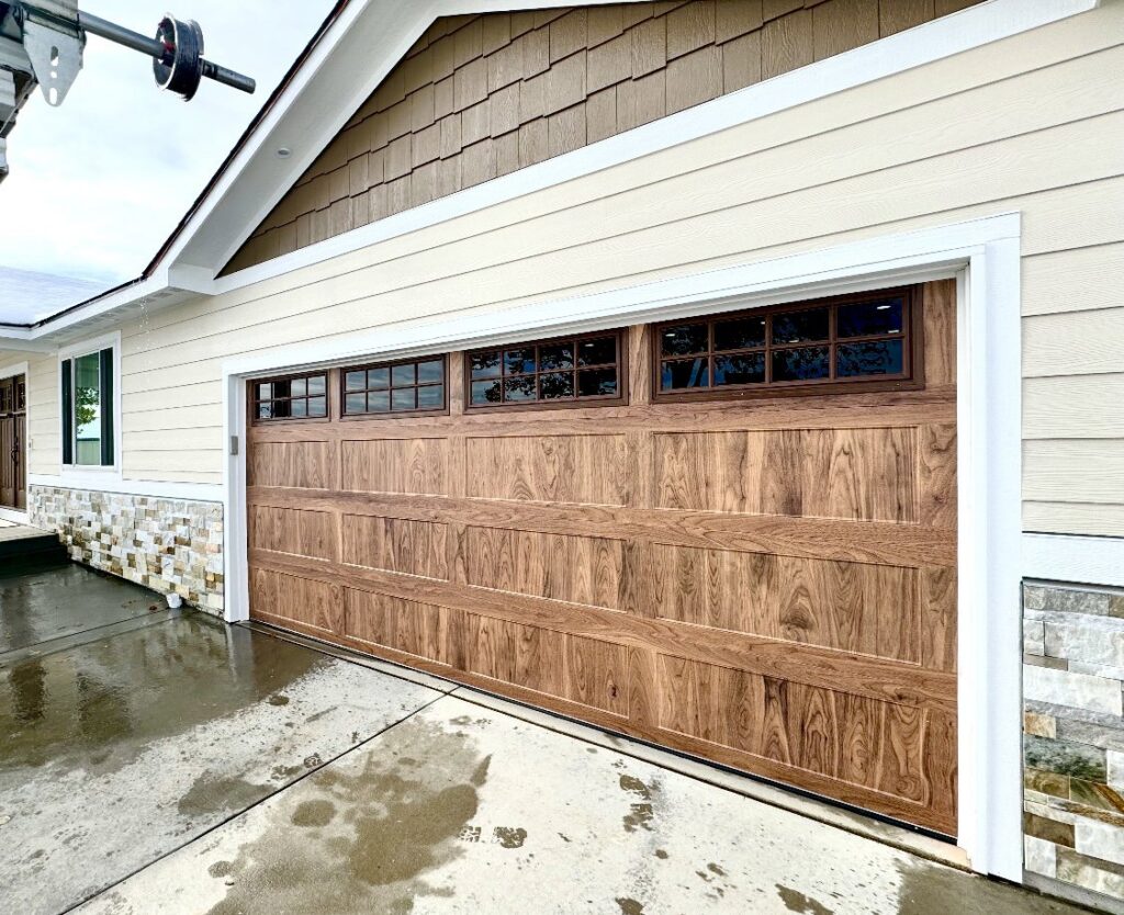 A beautiful wood-grain garage door with windows installed by Lion Heart Garage Doors in Thornton, CO.