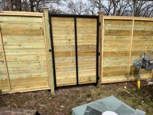 A new wood horizontal slat fence with a gate featuring a black metal frame by Fence Solutions of NWA in Gravette, AR.