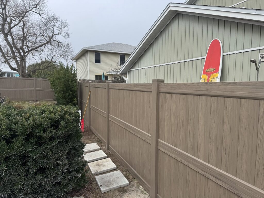 A durable wood-look composite fence installed around a residential property by Gaines Fence in Jacksonville, FL.