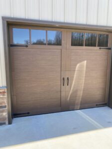 A brown wood-look garage door with top windows and decorative hardware installed by Smith's Garage Door in Clarksville, TN.