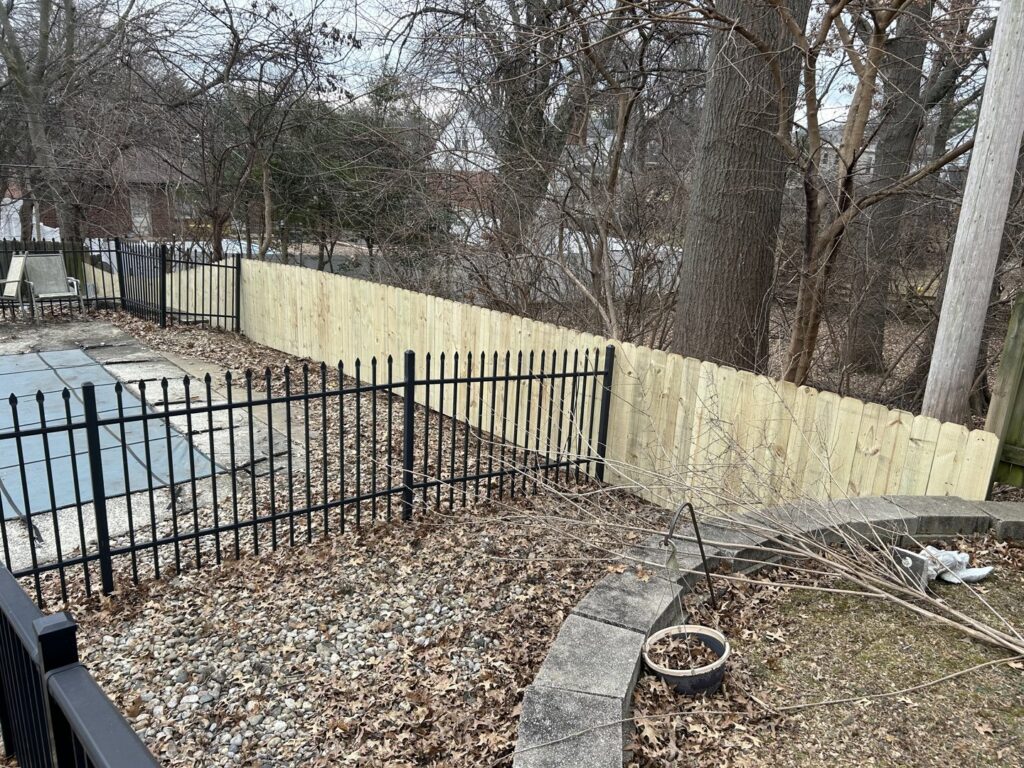 A combination wood privacy and black metal ornamental fence by Sexton Property Services STL in High Ridge, MO.
