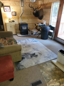 A cozy living room featuring a wood pellet stove with its chimney pipe and a floor vent, installed by AOK Handymen in Atco, NJ.