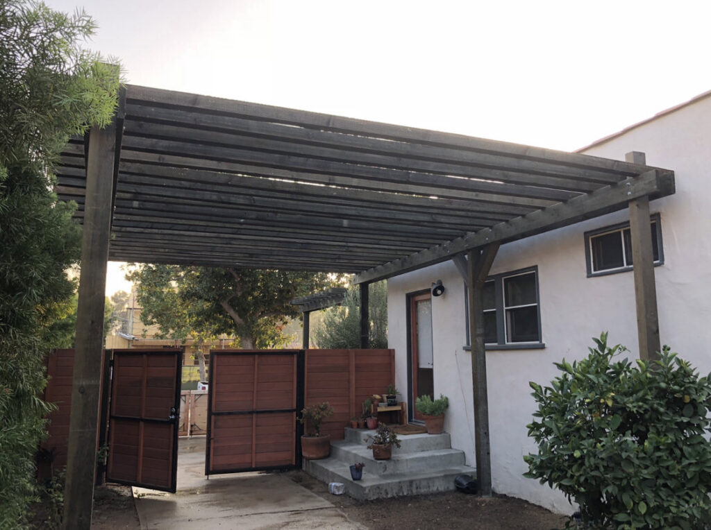 A wooden pergola with a matching horizontal slat gate installed by Los Angeles Fence Builders in Los Angeles, CA.