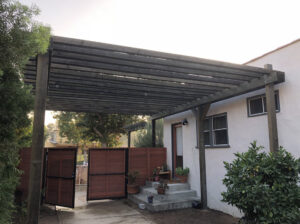A wooden pergola with a matching horizontal slat gate installed by Los Angeles Fence Builders in Los Angeles, CA.