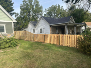 A newly installed wood picket fence running along the side of a residential house by Walker Fence in Council Bluffs, IA.