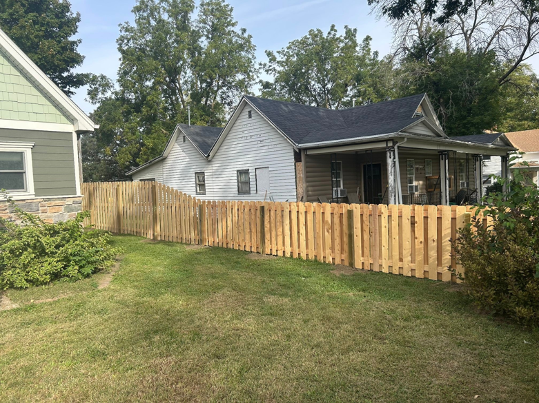 A newly installed wood picket fence running along the side of a residential house by Walker Fence in Council Bluffs, IA.