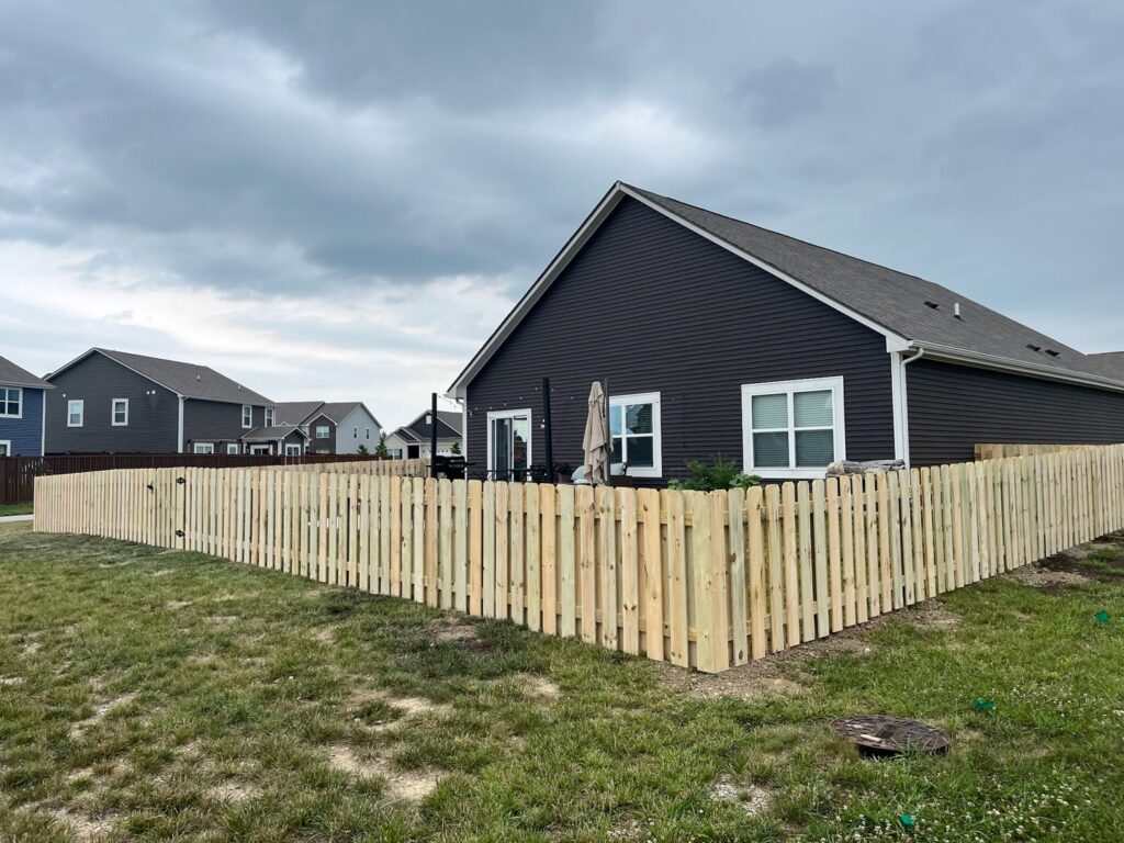 A wood picket fence enclosing a residential backyard, expertly installed by Render Fences in Fishers, IN.