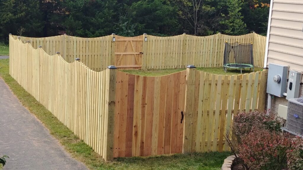 A wooden picket fence with a gate enclosing a backyard, installed by Universal Fence LLC in Drainesville, VA.
