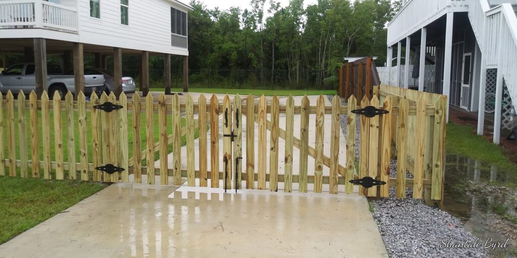 A charming wood picket fence with a double gate installed by FenceCo LLC for a coastal home in Pass Christian, MS.