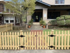 A newly installed wood picket fence with a double gate in front of a house by Premier Fence of Birmingham, LLC in Warrior, AL.