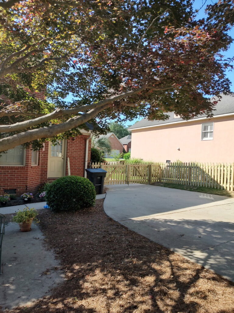 A wooden picket fence and gate installed along a driveway by CSRA Solutions in Jackson, SC.