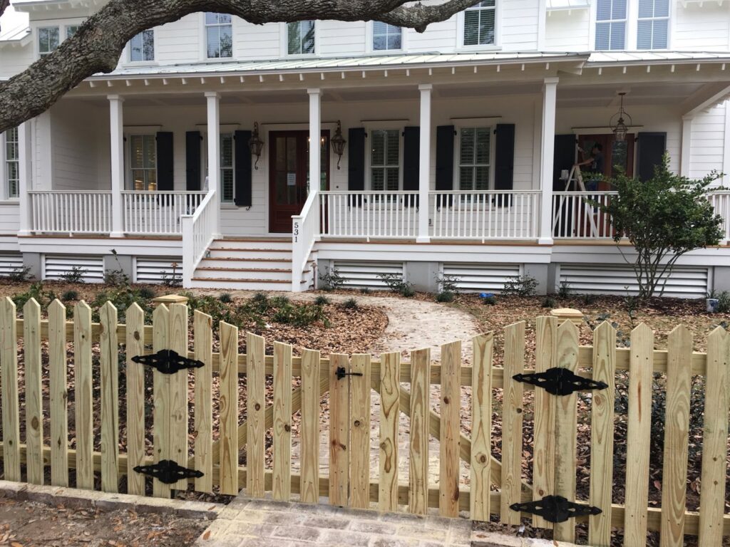 A charming wood picket fence with a functional gate in front of a home by Charleston Fencing Services in Moncks Corner, SC.