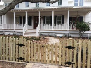 A charming wood picket fence with a functional gate in front of a home by Charleston Fencing Services in Moncks Corner, SC.