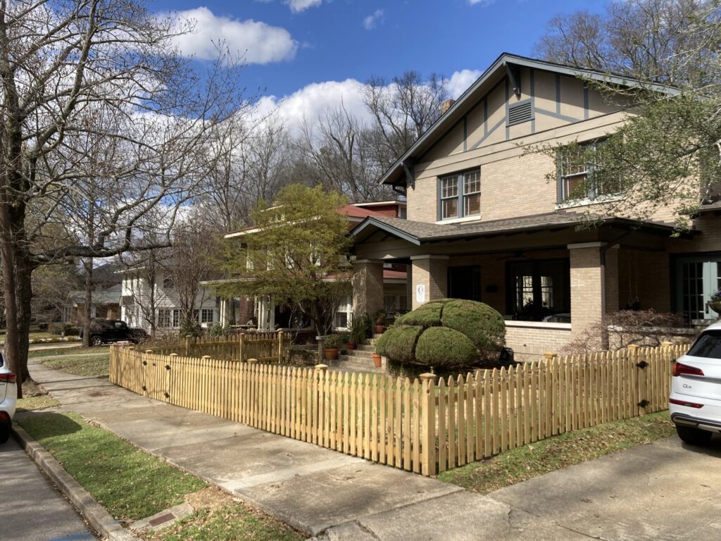 A newly installed wood picket fence with a double gate in a front yard by Premier Fence of Birmingham, LLC in Warrior, AL.