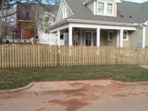A classic wood picket fence installed in the front yard of a residential home by Endurance Fence Solutions, LLC in Holly Springs, NC