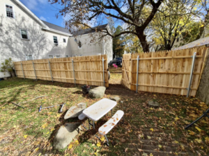 A newly installed wood picket fence with a gate in a residential backyard, completed by Dirigo Fence Company in Augusta, ME.