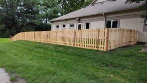 A newly installed wood picket fence along a sloped yard by Lujan Fencing in Independence, MO.