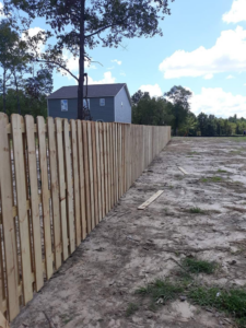 A newly installed wood picket fence along a property line by Rowe Fence & Supply in New Kent, VA.
