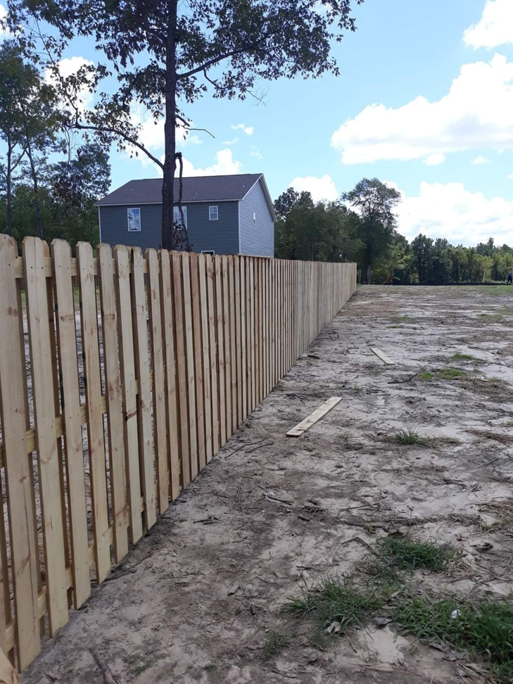 A newly installed wood picket fence along a property line by Rowe Fence & Supply in New Kent, VA.