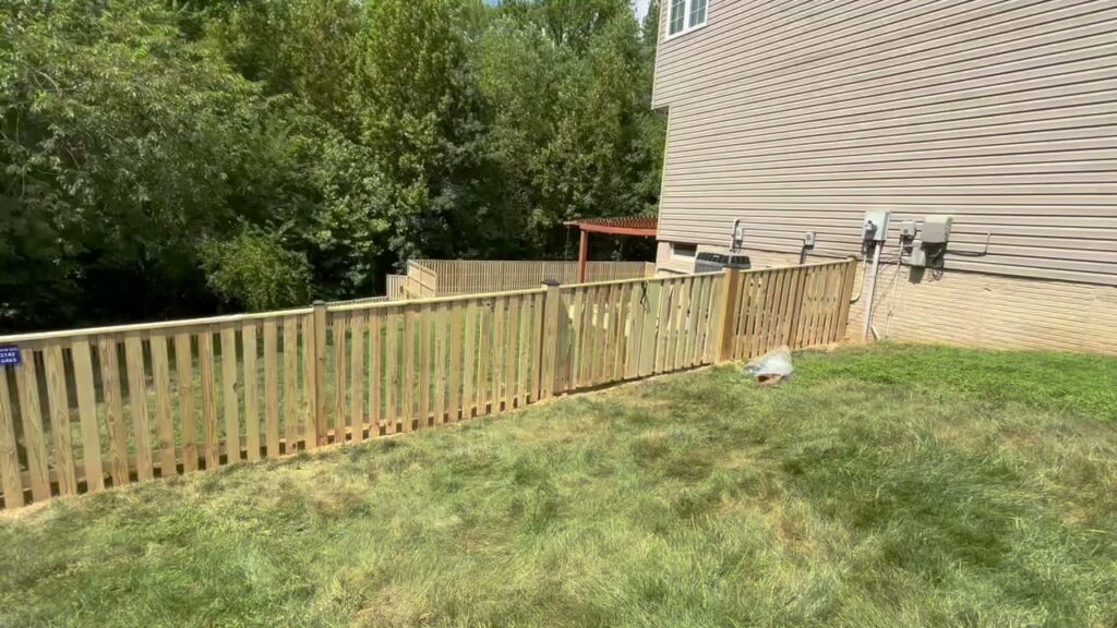 A wooden picket fence installed along the side of a residential house by Universal Fence LLC in Drainesville, VA.