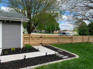 A natural wood picket fence with a gate installed next to a home by AmeriDream Fence & Deck in Joliet, IL.