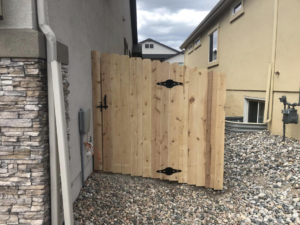 A new wooden picket gate with decorative black hinges, installed by Master Fence Builders in Fort Smith, AR.