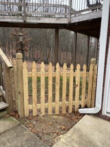 A small wood picket gate installed under a deck for child or pet safety by Top Rail Fence Birmingham, AL