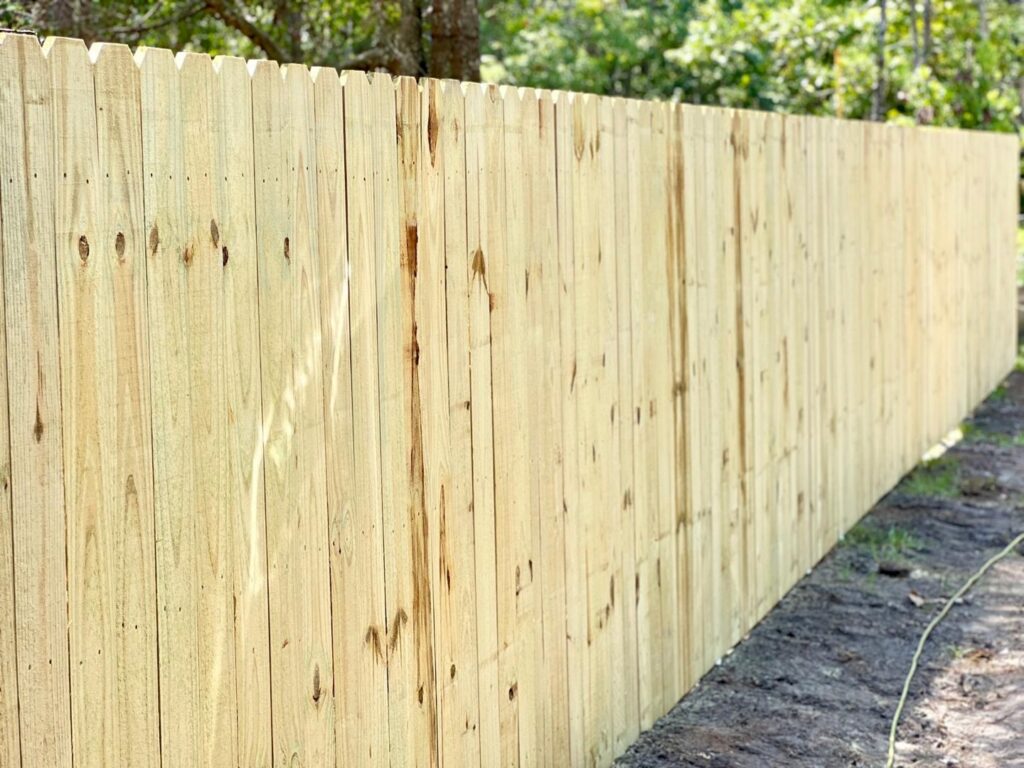 A newly constructed wood picket privacy fence for a residential property by Boost My Home in St. Augustine, FL.