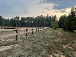 A long wooden post-and-rail fence installed on a rural property by Jaguar Fence LLC in Mobile, AL.