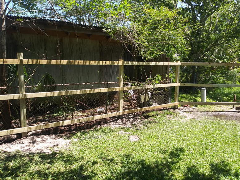 A newly installed wood post and rail fence with wire mesh, perfect for property lines, by Country Boyz fencing in Biloxi, MS.
