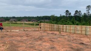 Fencing contractors installing a wood privacy fence and split rail fence on a property by Precision Fence in Meridian, MS.
