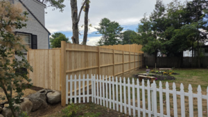 A combination of a new wooden privacy fence and a white picket fence installed by Creative Fence in Casco, ME.