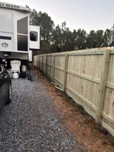 A sturdy wood privacy fence installed by FenceCo LLC along a gravel driveway in Pass Christian, MS.