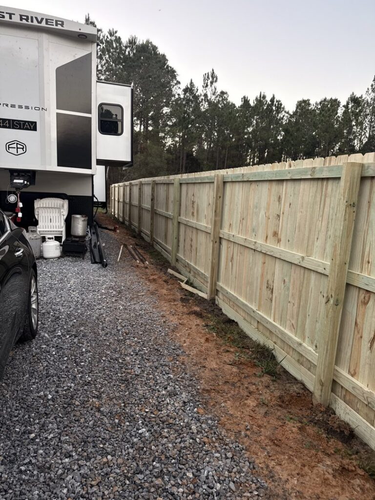 A sturdy wood privacy fence installed by FenceCo LLC along a gravel driveway in Pass Christian, MS.